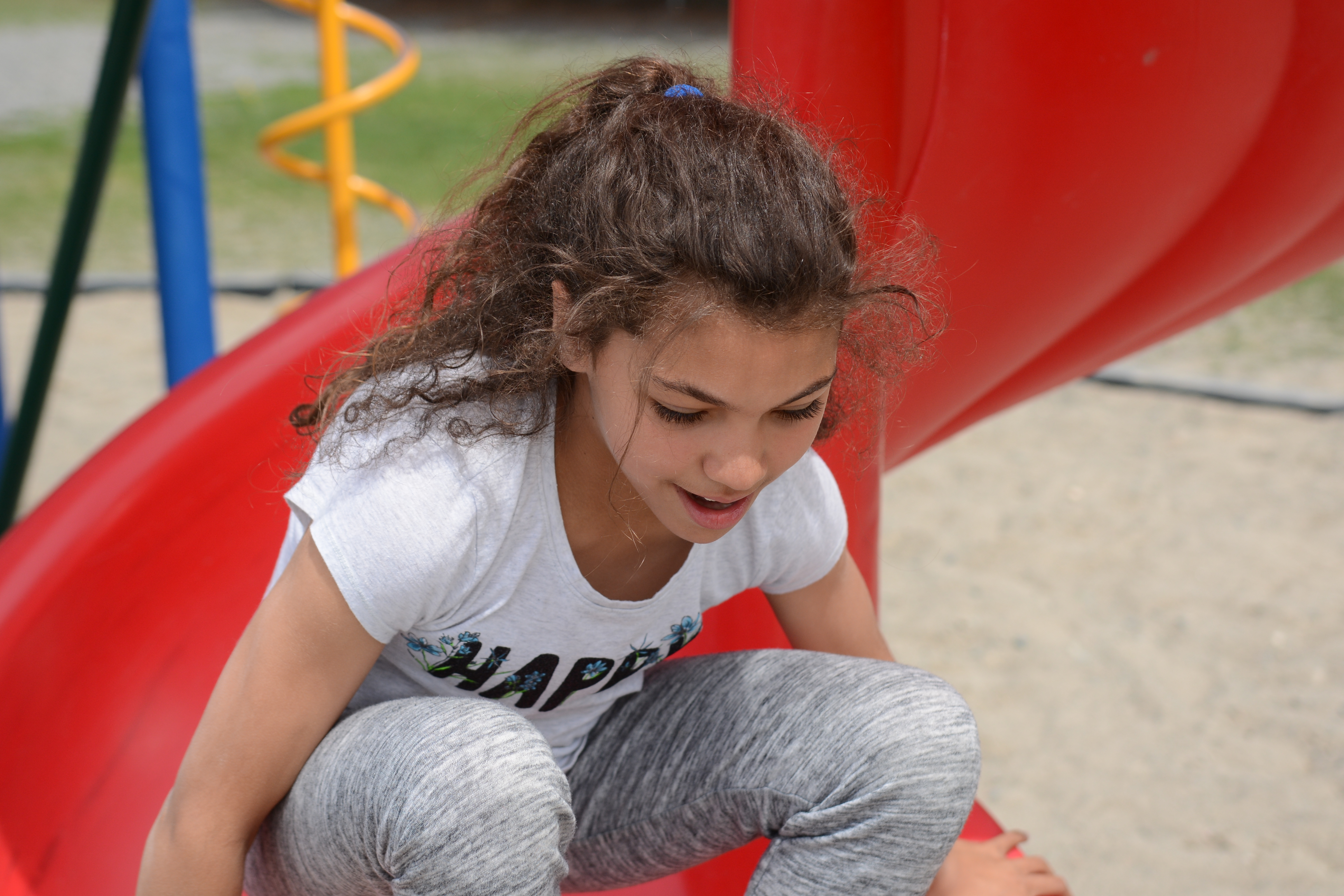 A girl sits on a red slide.